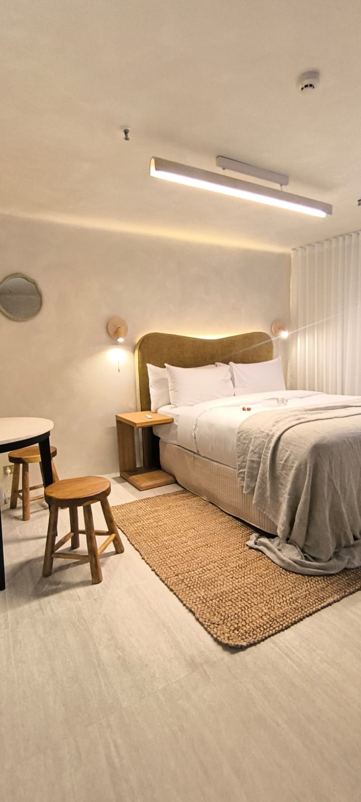Habitación boutique con cama, iluminación cálida y textiles naturales